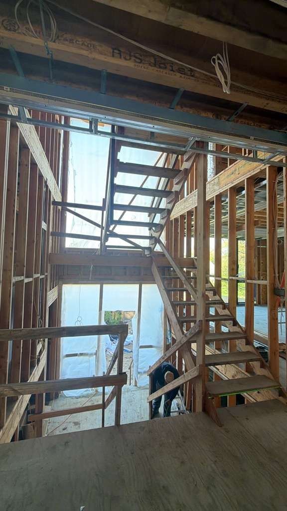Black steel staircase stringers leveled in an unfinished wood-framed opening.